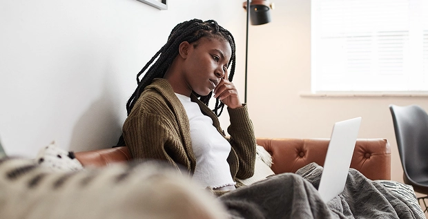 woman sitting on couch using laptop